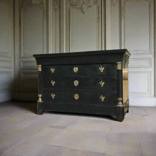 Black dresser with gold accents in a room with white paneled walls.