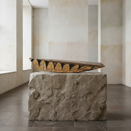 A large fragment of a wooden structure with a design resembling acanthus leaves, placed on a wooden surface against a plain background.